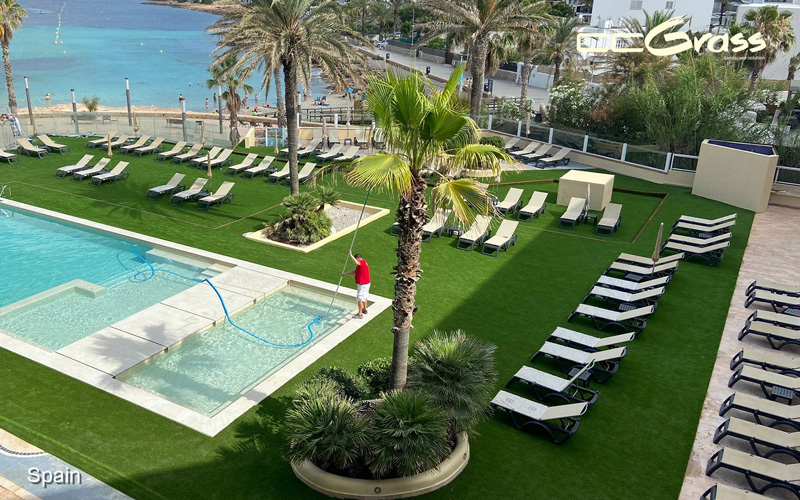 Exquisito paisaje de grass sintético en la zona de piscinas de un hotel